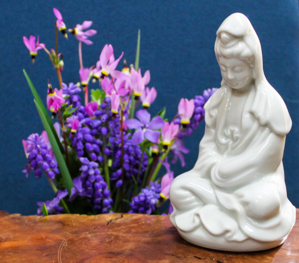 White statue of Kuan Yin with blue flowers